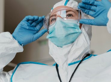 doctor-putting-protective-goggles_23-2148847202